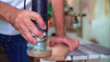 Bir marangozun elektrikli aletle mobilya işçiliğinin kenarlarını düzeltirken yavaş çekim görüntüsü. Ahşap işleme