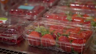 Süpermarketin açık buzdolabında ya da markette taze çilek dolu sıra sıra plastik kaplar.