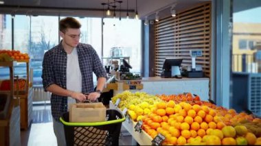 Adam organik gıda dükkanından alışveriş yapıyor, turunçgil meyveli limonu seçiyor, sağlıklı ve vitaminli C vitamini meyvesi alıyor, yararlı beslenme