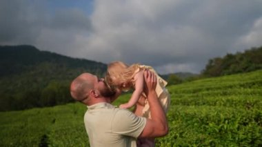 Baba küçük tatlı kızını elinde tutuyor ve kaldırıyor, şefkatle öpüyor, neşeli küçük kız babasıyla gülüyor, mutlu aile anları.