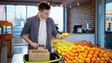 Markette elinde turunçgil meyvesi olan bir market müşterisi. Limonlara bakıyor ve onları çevre dostu kese kağıdına koyuyor. Meyve ve sebze almaya. Vejetaryen yaşam tarzı