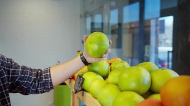 Adam süpermarketten meyve alıyor, raftan oroblanco meyvesi alıyor, C vitamini ile sağlıklı narenciye alıyor, erkek eli ve yeşil şeker meyvesi yakın plan çekiyor.