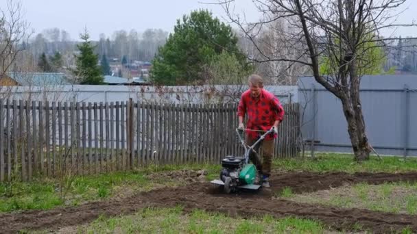 Starší muž orá půdu kultivátorem nebo špalkem — Stock video
