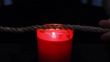 Shibari ritüeli için mum ışığında jüt halatı yakmak.