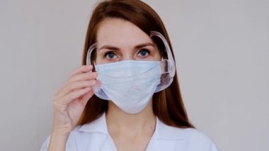 Önlüklü doktor portresi. Korunaklı şapkalı ve yüz maskeli bir kadın doktor. Koronavirüse karşı güvenlik önlemleri almış.