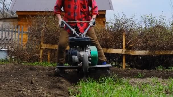 Hombre de edad avanzada araña el suelo con un cultivador o un bloque de labranza — Vídeos de Stock