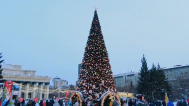 Novosibirsk, Rusya, 31.12.2020: Noel ağacı yakınlarındaki halk festivalleri ve kırmızı yıldız, balon ve çelenk şeklinde yeni yıl süslemeleri