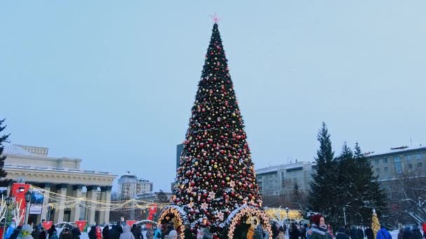 Novosibirsk, Rusland, 31.12.2020: Volksfeesten van mensen in de winter bij de kerstboom en nieuwjaarsdecoratie in de vorm van een rode ster, ballonnen en bloemenslingers — Stockvideo