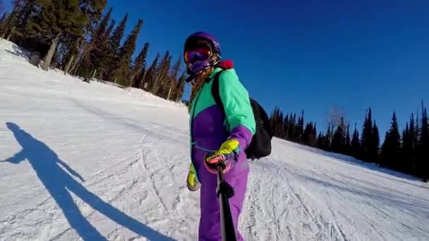 Sheregesh, Rusko, 02.21.2020: Žena snowboardistka jezdí na snowboardu z hory a natáčí selfie na kameru