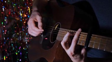 Gitaristlerin eli akustik gitarda solo çalıyor. Bir adam müzik aletinin tellerini koparıyor.