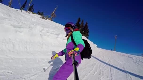 Sheregesh, Rosja, 02.21.2020: Kobieta snowboardzistka zjeżdża z góry na snowboardzie i robi selfie przed kamerą — Wideo stockowe