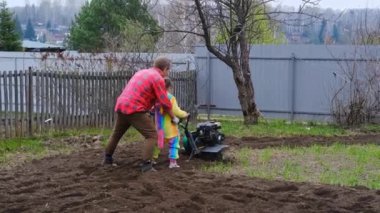 Tek boynuzlu at kostümü giymiş çocuklar yaşlı bir dedeye bahçede tarla sürmede yardımcı oluyor.