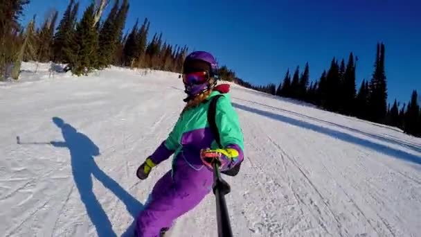 Sheregesh, Rusko, 02.21.2020: Žena snowboardistka jezdí na snowboardu z hory a natáčí selfie na kameru — Stock video