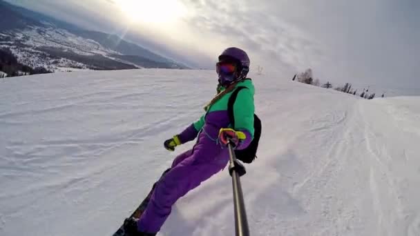 Sheregesh, Russia, 02.21.2020: Woman snowboarder rides a snowboard down a mountain and shoots selfie on camera — Stock Video