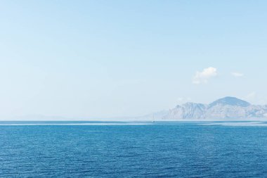 Mavi deniz yüzeyinde turistlerle dolu bir tekne. Doğa arkaplanı