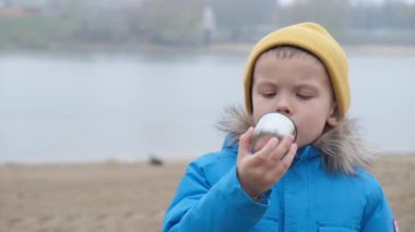 Soğuk bir günde, bir çocuk bir nehrin zemininde çay içiyor.