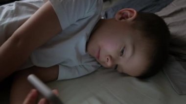 five year old boy in bed with a smartphone