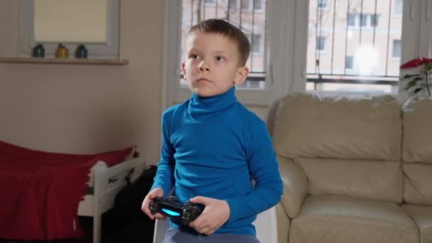 Een vijfjarige jongen speelt een console — Stockvideo
