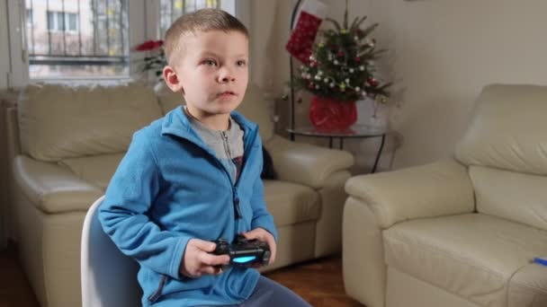 5歳の男の子がクリスマスツリーの近くでゲーム機をプレイする — ストック動画