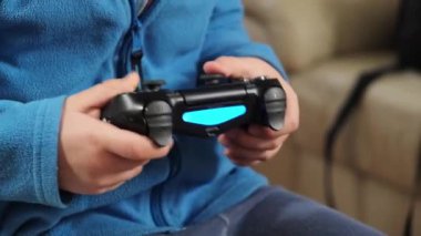 Oyun konsoluyla oyun oynayan 5 yaşındaki bir çocuğun elleri.