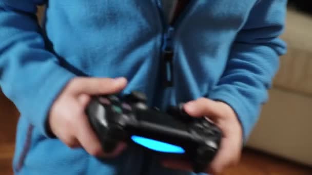 Händerna på en femårig pojke som spelar en spelkonsol med en joystick — Stockvideo