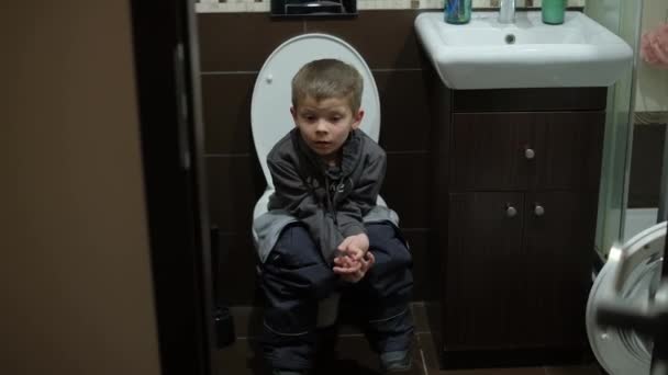 Ένα αγόρι κάθεται στην τουαλέτα στην τουαλέτα — Αρχείο Βίντεο