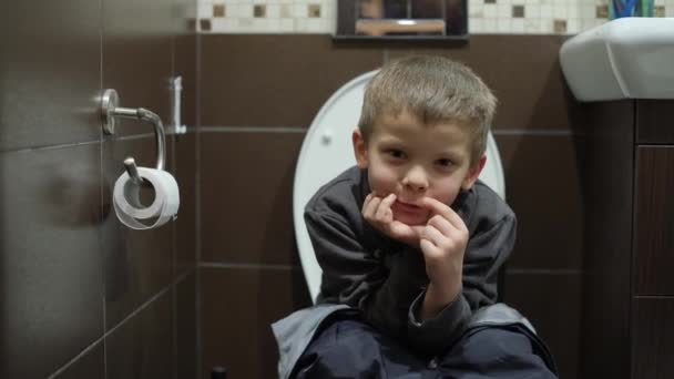 Chłopiec siedzi na toalecie w toalecie — Wideo stockowe