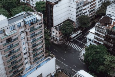 Islak asfalt ve bir yerleşim bölgesindeki bir grup ev ve ağaçla dolu yağmurlu bir günde, bir zebra yaya geçidi olan kavşağın yukarısından insansız hava aracı görüntüsü