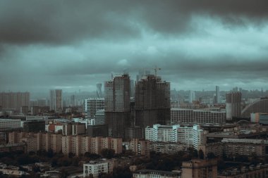 Fırtınalı bir günde şehrin yerleşim bölgesinin insansız hava aracı görüntüsü. İnşaat ve yağmur bulutları altında gökdelenleri olan metropolitan bir şehrin hava manzarası. Ticari ve konut binalarının hava görüntüleri
