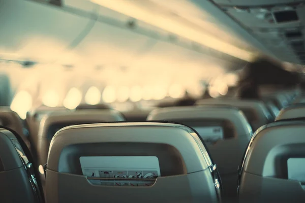 飛行場の浅い深さの旅客機の長いキャビンとその後ろのポケットに安全上の指示を持つ座席の最も近い空の行に選択的焦点 航空機の窓のボケ — ストック写真