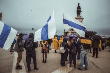 Lizbon, Portekiz - 20 Mart 2022: Ukrayna 'yı desteklemek ve Rus işgali ve saldırganlığına karşı bir protesto eylemi: sahnenin yanında savaş karşıtı mavi ve beyaz bayraklı bir grup protestocu