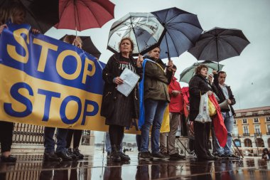 Lizbon, Portekiz - 20 Mart 2022: Rusya 'nın işgali ve agresif savaşa karşı Ukrayna' yı destekleyen bir protesto eylemi: Şemsiye altında protestocuların bulunduğu bir sahne, şiddetli yağmur, megafon kullanan bir kadın