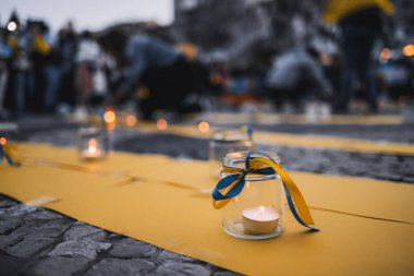 Lisbon, Portugal - April 20, 2022: lit candles wrapped in ribbons in the colors of the Ukrainian flag, in memory of those who died in Mariupol during a protest rally in saving Mariupol