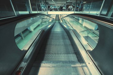 Uluslararası bir havaalanı veya alışveriş merkezinde veya demiryolu deposunda neon ışıkla aydınlatılmış modern bir krom yürüyüş yolunun iç görünümü, travelatörün girişine seçici bir odak ile