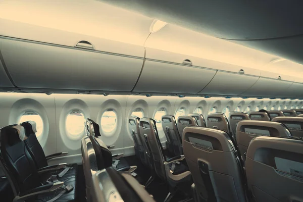 飛行機のエコノミークラスのプラスチックシートの行が空の旅客機の長いキャビンの広角ビューで その反対側のポケットに安全上の指示がある — ストック写真