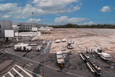 Havaalanı yardımcı bakım ekipmanlarının geniş açılı görüntüsü: römorklar, traktörler, konteynırlar, arabalar, iskeleler - her şey kalkış pistinin uçuş kapısına yakın.