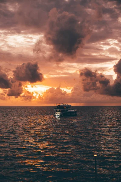 一个垂直的海景 夕阳西下 天空令人叹为观止 一艘远洋游艇的轮廓在海浪中荡漾 一个金色的时辰 在海里 一只小船在水面上荡漾 — 图库照片