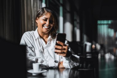 Kahkaha atan, iri yarı, İspanyol bir girişimcinin, kahve molası sırasında karanlık bir kafede otururken bir meslektaşıyla telefon görüşmesi yaparken kahkahalarla gülmesinin portresi.