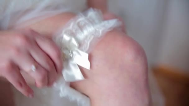 Femme portant une jarretière sur la jambe. La mariée tient en main une jarretière perdue dans une chambre d'hôtel. préparation matinale concept de mariage . — Video