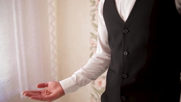 El hombre lanza y atrapa anillos de bodas de oro en la palma de su mano. — Vídeo de stock