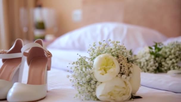 Chaussures de mariée avec un bouquet de fleurs sur le lit de l'hôtel. — Video