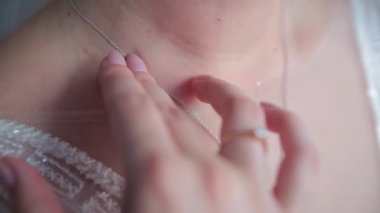 Genç bir kadın boynuna kolyeye dokunuyor..