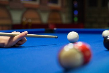 Bilardo oyunu devam ediyor, oyuncu ıstakayla topa vurmayı hedefliyor