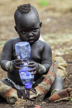 Omo Nehri Vadisi, Etiyopya, Kasım 2020, Mursi kabilesinden küçük bir çocuk yerde oturuyor.