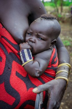 Omo Nehri Vadisi, Etiyopya, Kasım 2020, Mursi kabilesinde annesiyle birlikte bir bebek.