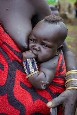 Omo Nehri Vadisi, Etiyopya, Kasım 2020, Mursi kabilesinde annesiyle birlikte bir bebek.