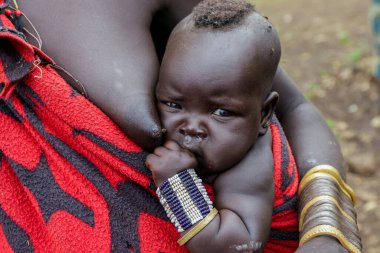 Omo Nehri Vadisi, Etiyopya, Kasım 2020, Mursi kabilesinde annesiyle birlikte bir bebek.