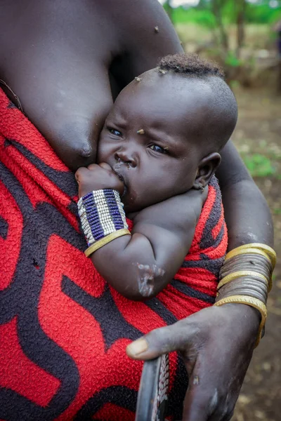 Omo Nehri Vadisi, Etiyopya, Kasım 2020, Mursi kabilesinde annesiyle birlikte bir bebek.