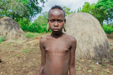 Omo Nehri Vadisi, Etiyopya - 29 Kasım 2020: Yerel Mursi kabilesi köyünde büyük ve geleneksel ahşap küpeli Afrikalı bir gencin portresi)