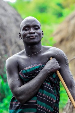 Omo Nehri Vadisi, Etiyopya - 29 Kasım 2020: Mursi kabile köyünde geleneksel giysili Mutlu ve Tatmin Edilmiş Afrikalı Adam Portresi